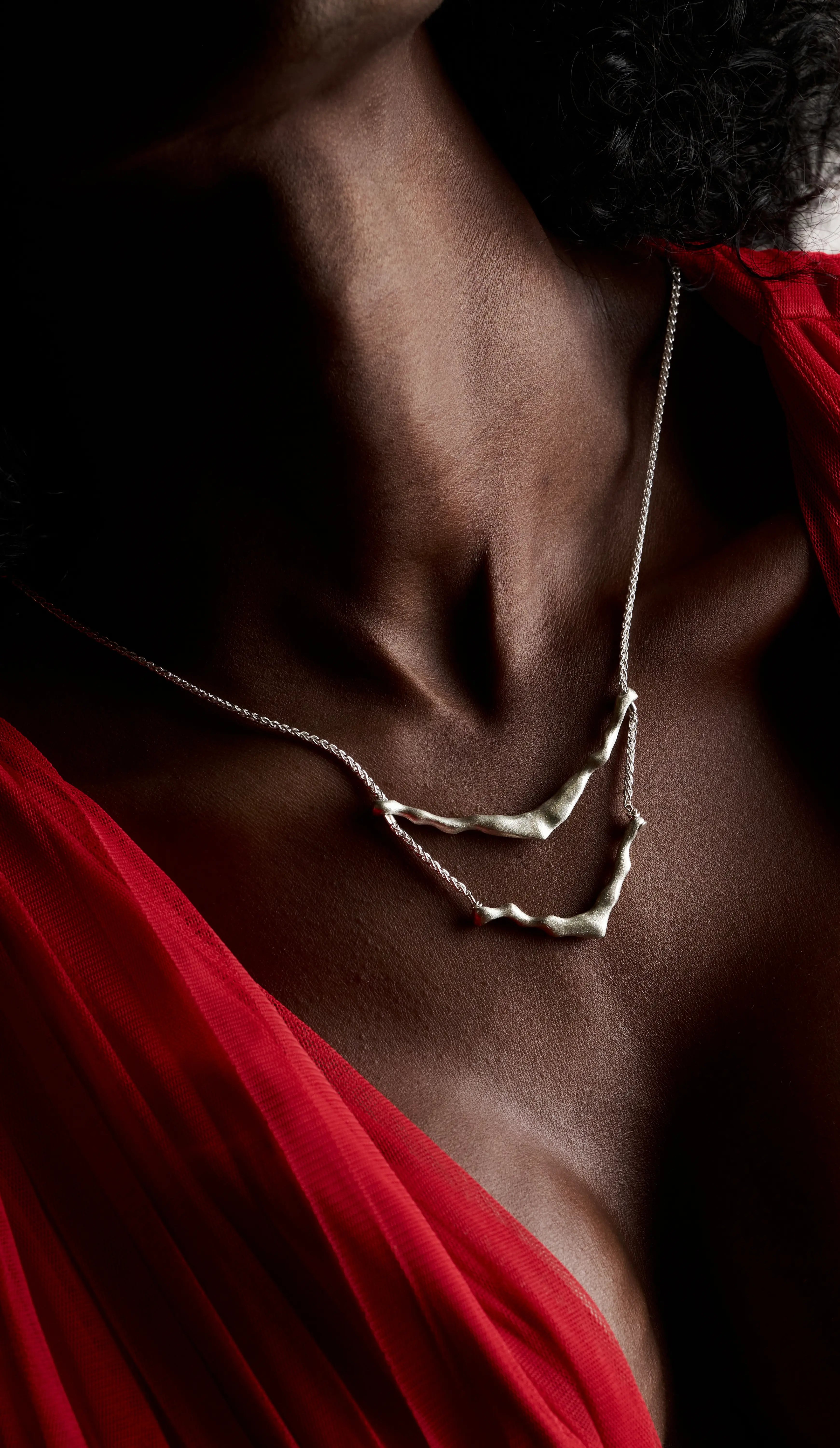 Femme portant le collier de dos Exo en argent avec un vêtement rouge.