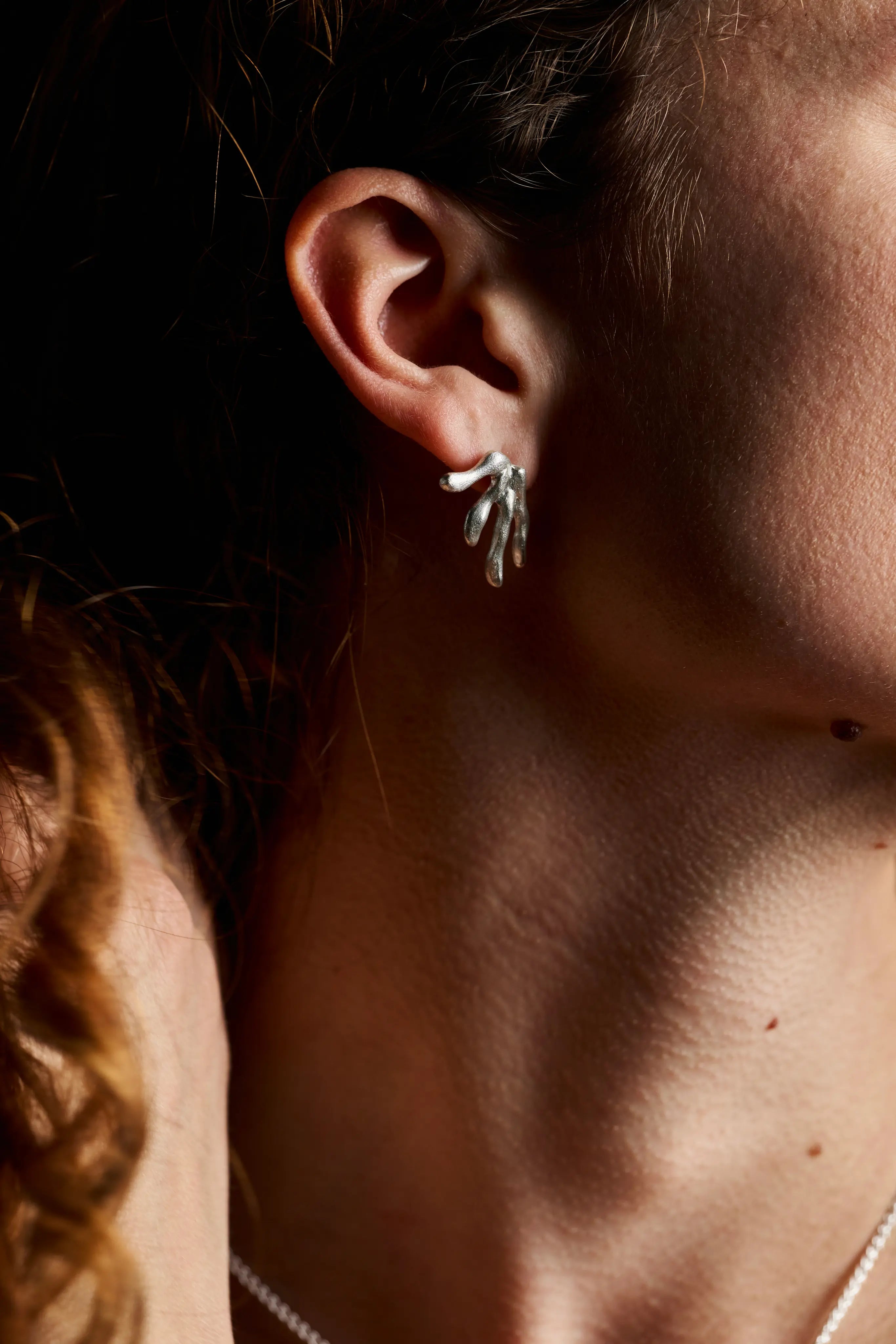 Vue de près d'une femme portant la boucle d'oreille Ména en argent. Création française éthique.