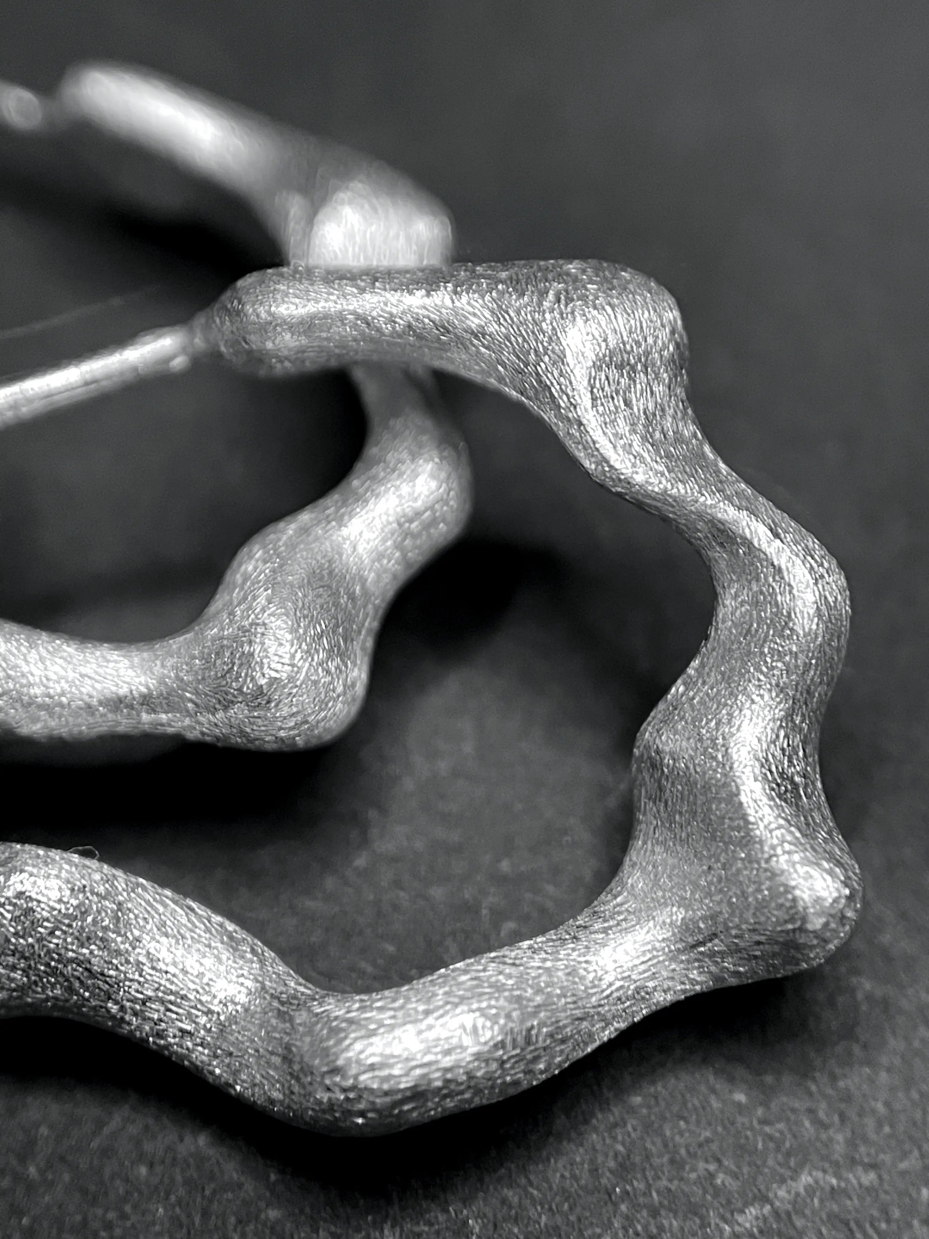 Macro des boucles d'oreilles Spira, montrant la texture fait main de l'argent 925.