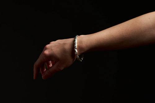 Gros plan du bracelet Fracta en argent sur le poignet. Design fait main unique.