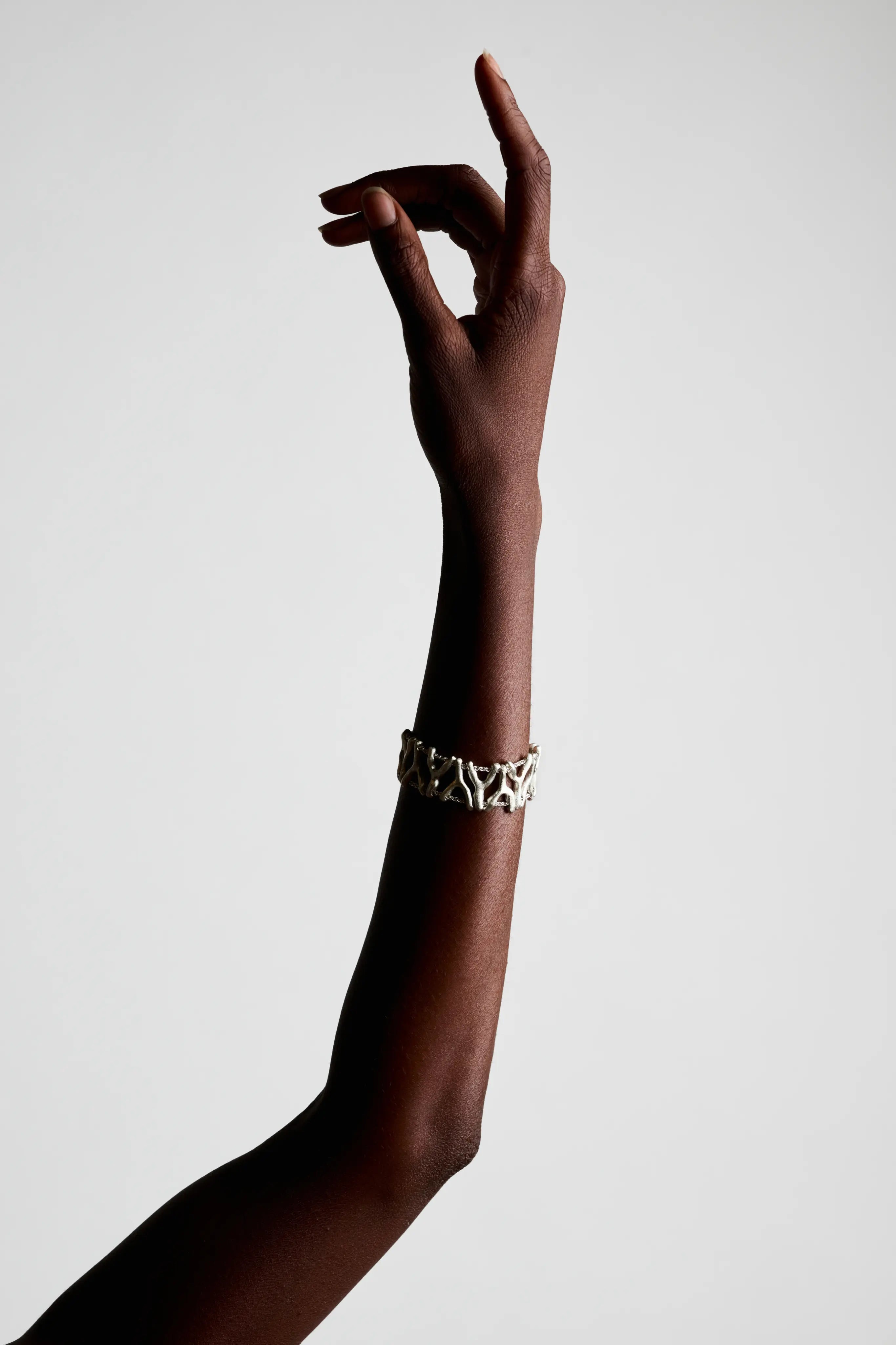 Bras portant le bracelet Isopora en argent 925. Création éthique et durable.