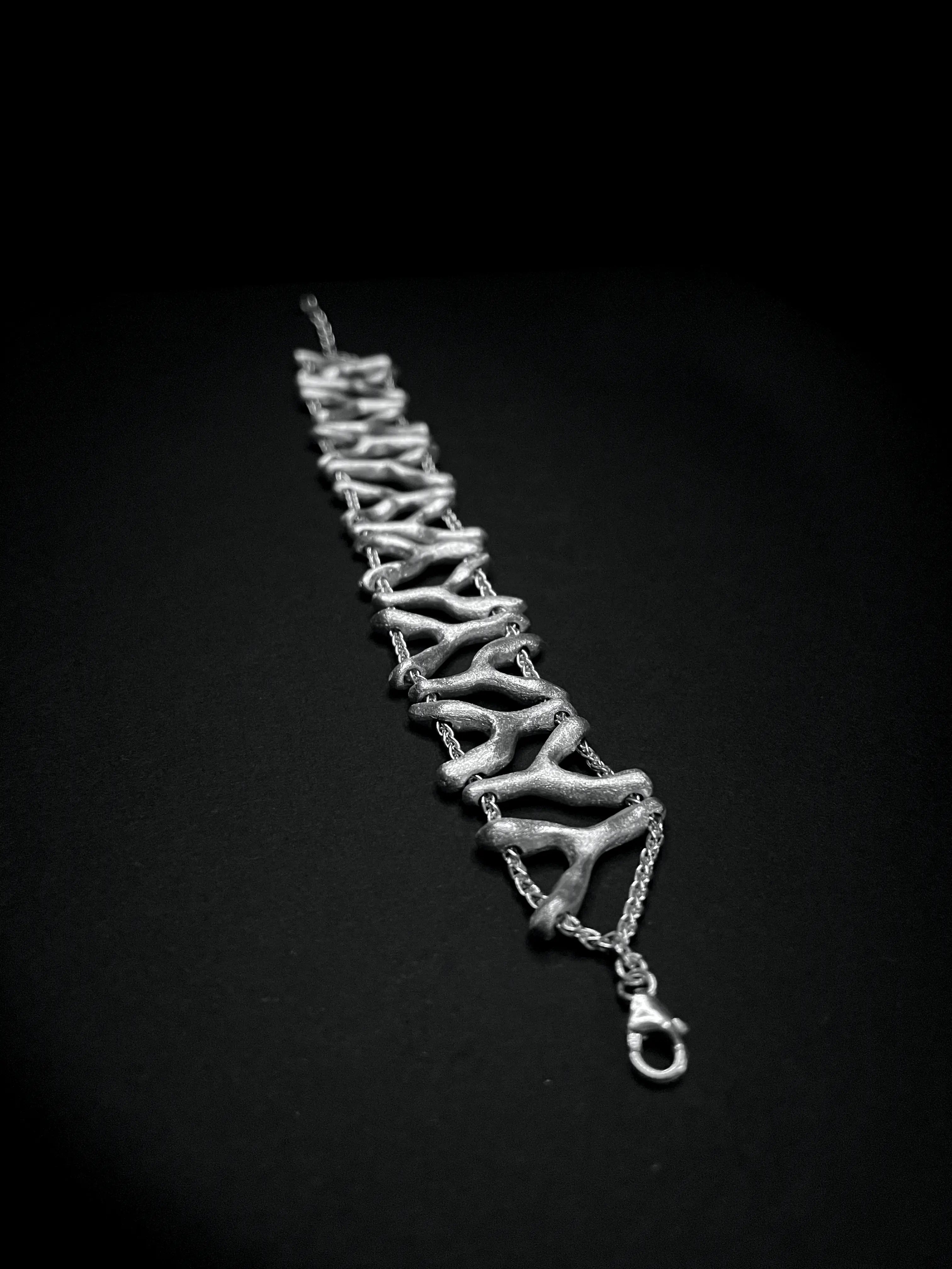 Bracelet Isopora en argent, design ajouré, sur fond noir. Collection Corail éthique.