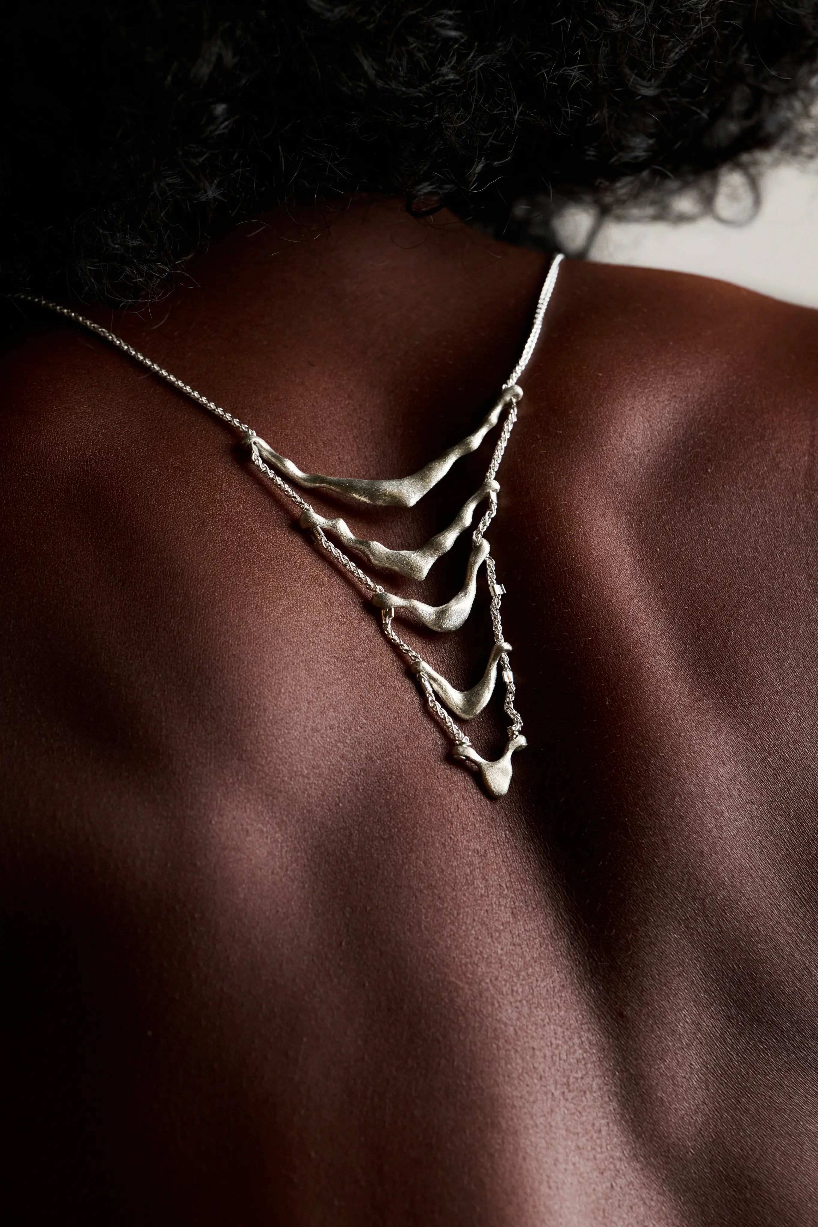 Gros plan du collier de dos Exo porté sur le dos nu. Bijou fait main par Synonys.