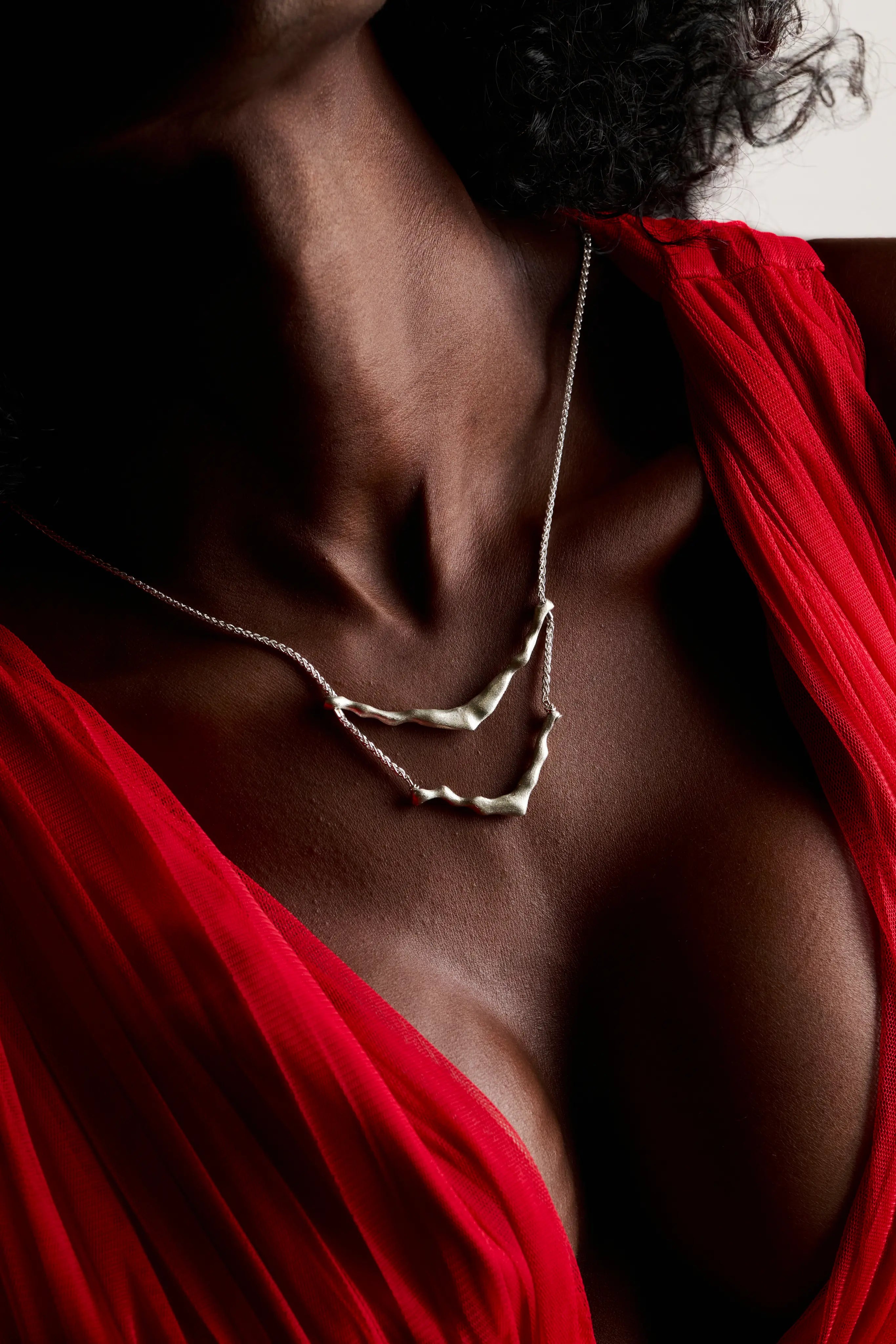 Femme portant le collier de dos Exo en argent avec un vêtement rouge.