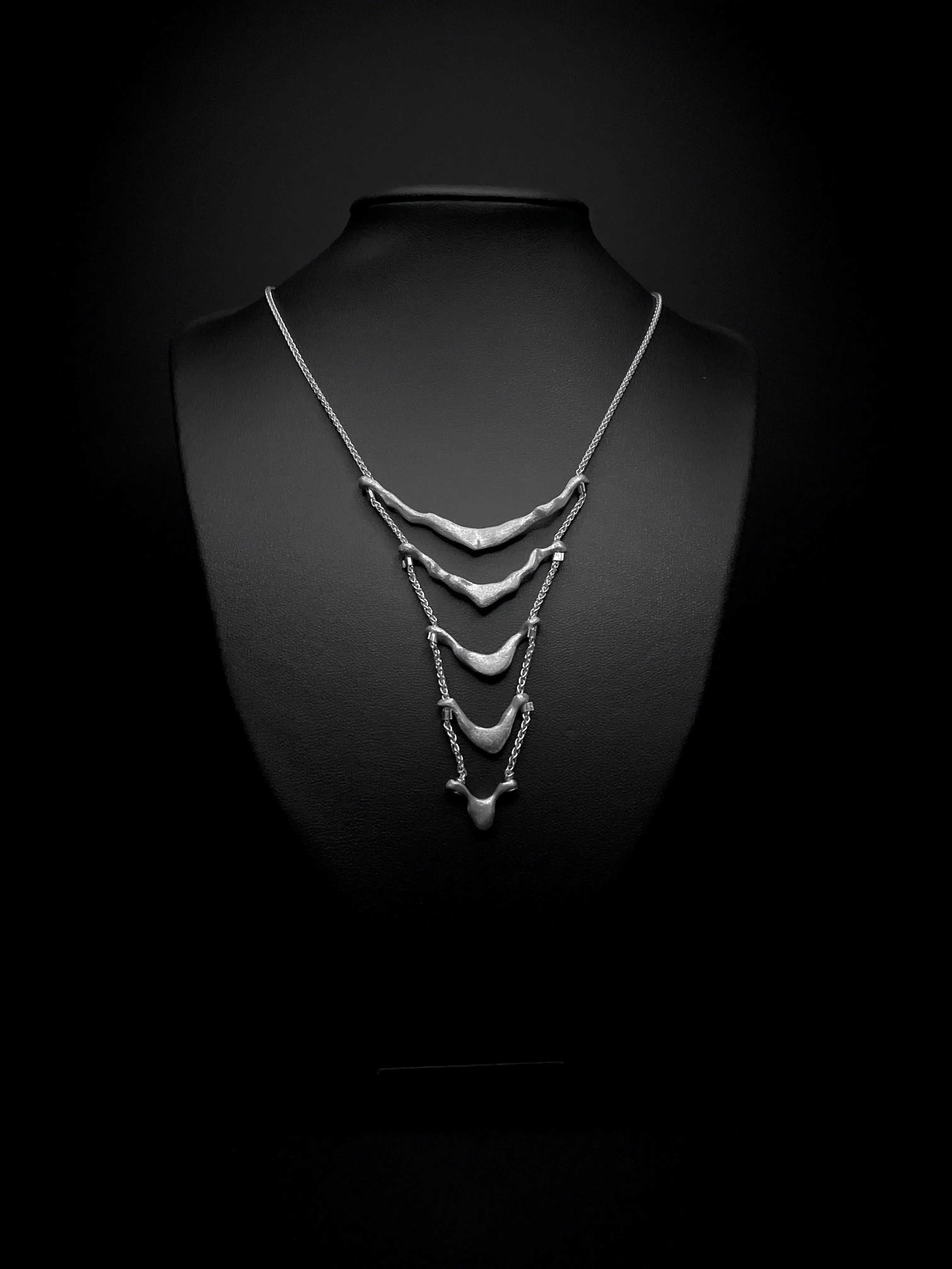 Vue de face du collier de dos Exo en argent avec détail de perles d'argent.