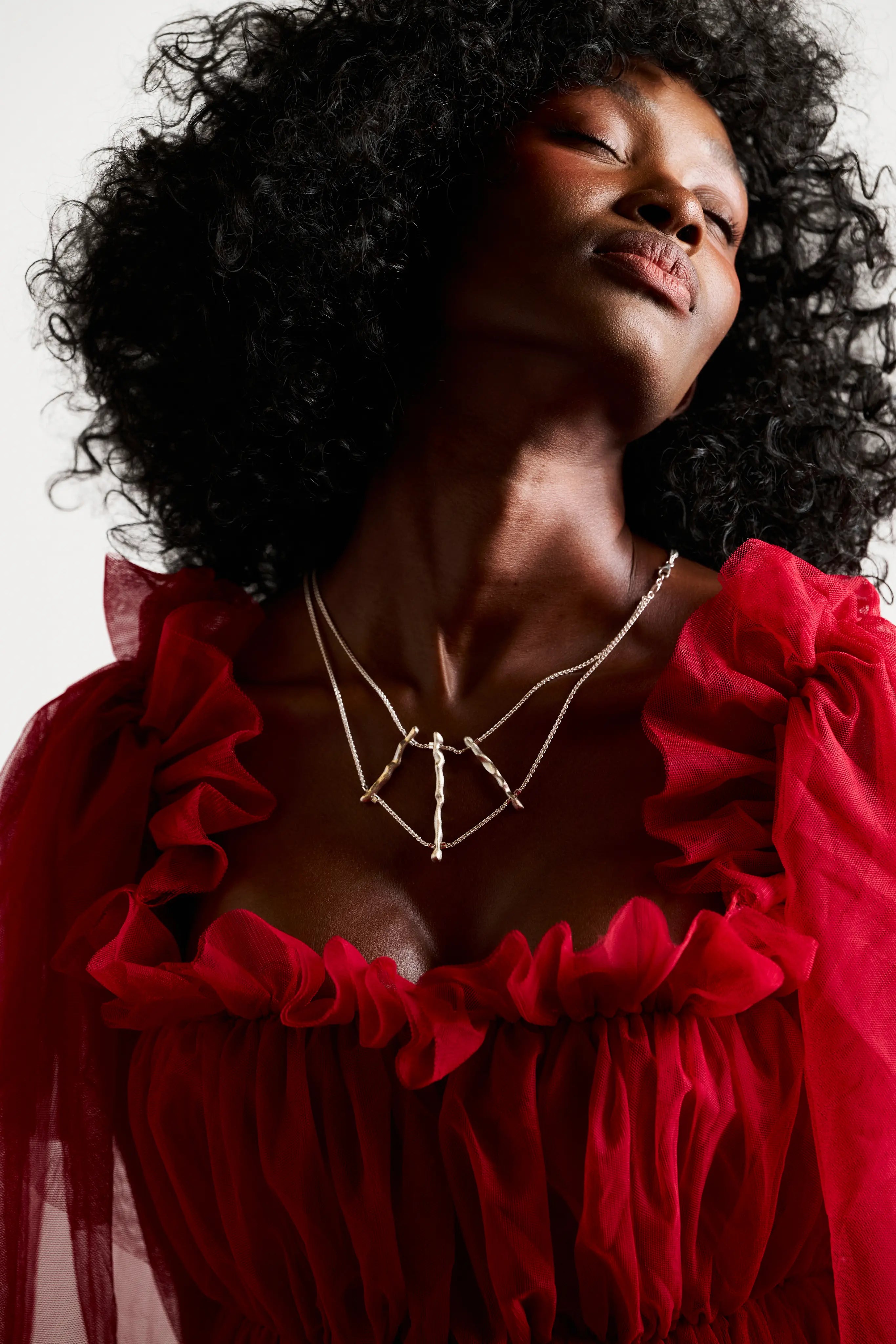 Collier de dos Osso Synonys en argent 925 et perles d'argent, porté sur une femme en robe rouge. Bijou fait main, collection Corail.