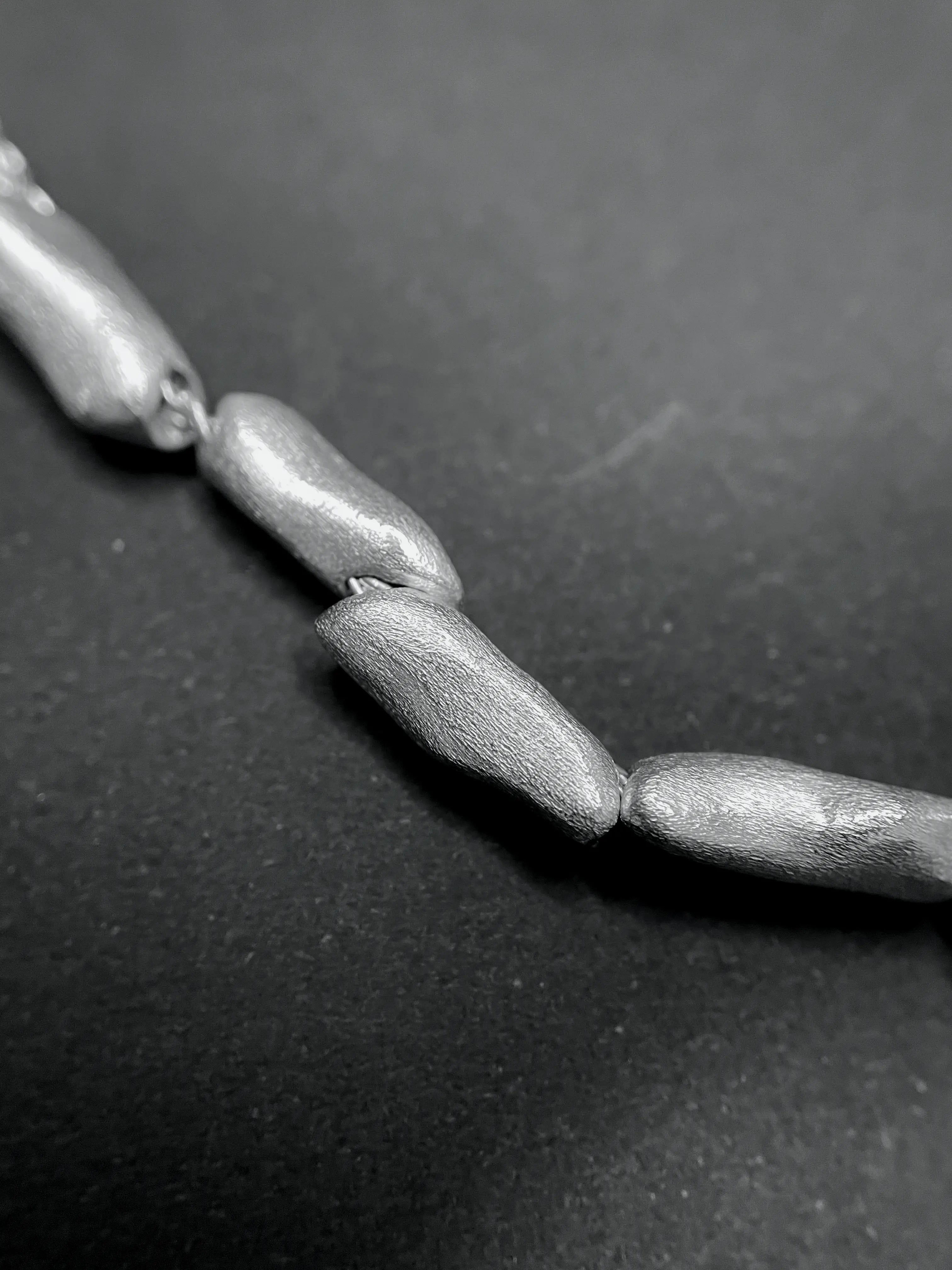 Macro du pendentif du collier Fracta montrant la texture et les perles d'argent.