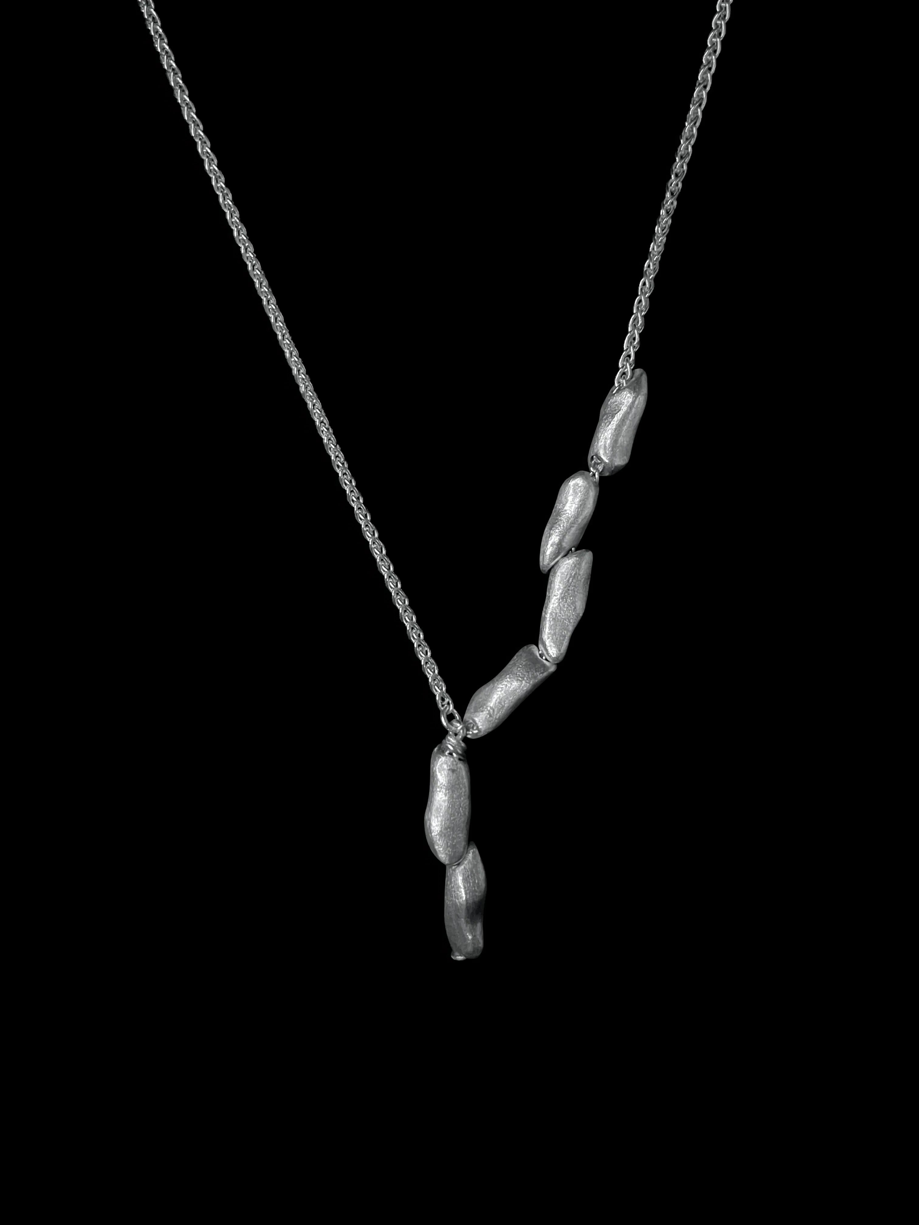 Vue complète du collier Fracta Synonys en argent 925 sur fond noir. Bijou fait main.