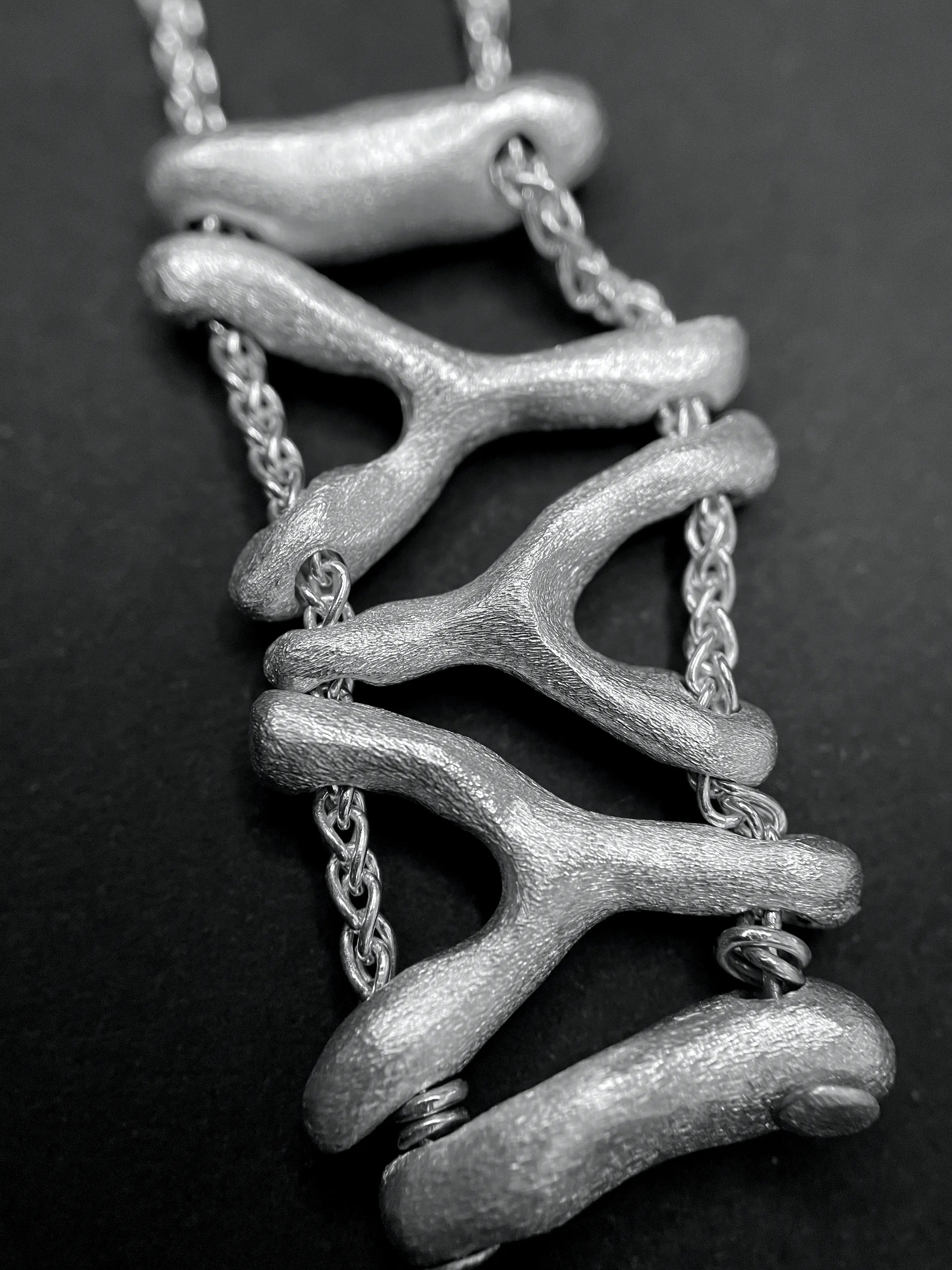 Macro du pendentif du collier Isopora, accentuant le travail fait main des perles.