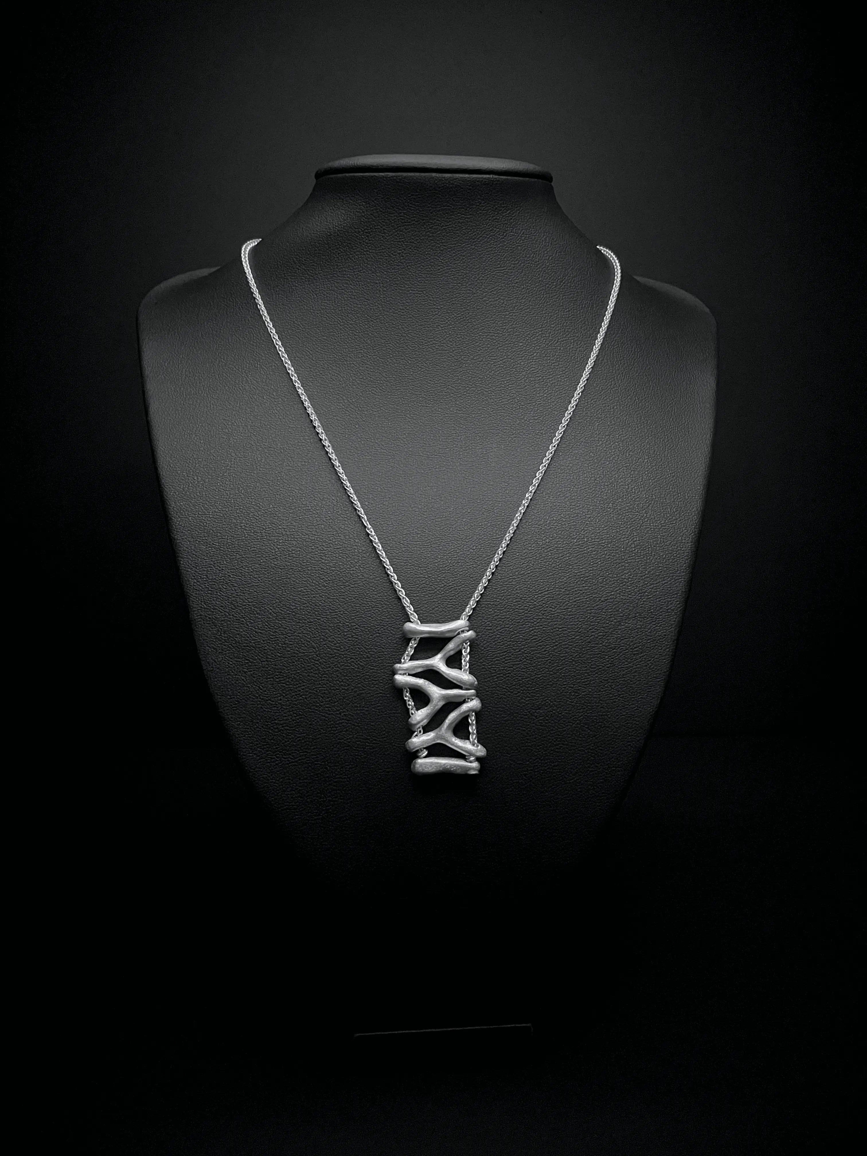 Pendentif du collier Isopora en argent sur fond sombre. Collection Corail éthique.