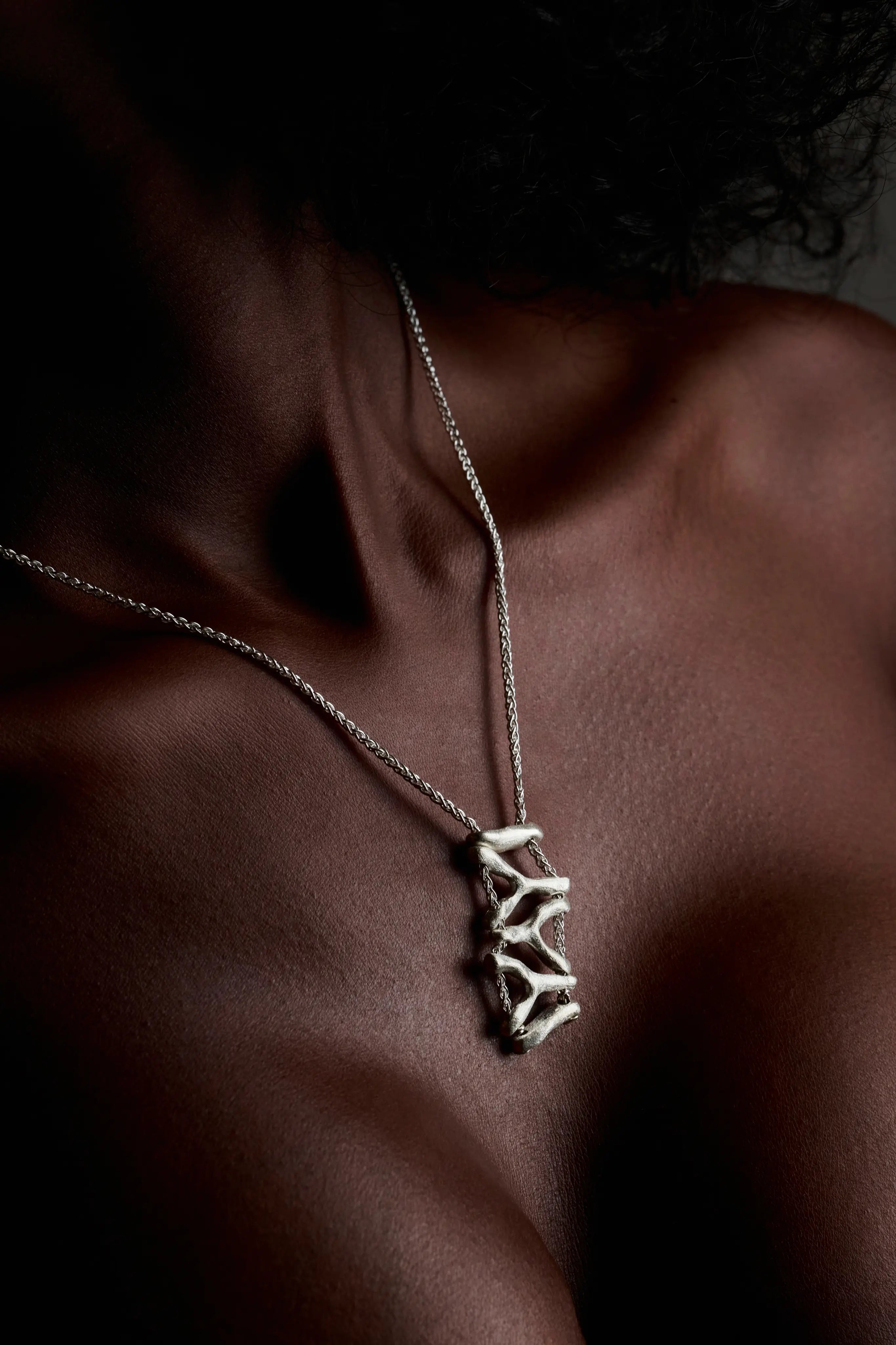 Femme portant le collier Isopora en argent sur le décolleté. Bijou artisanal et élégant.