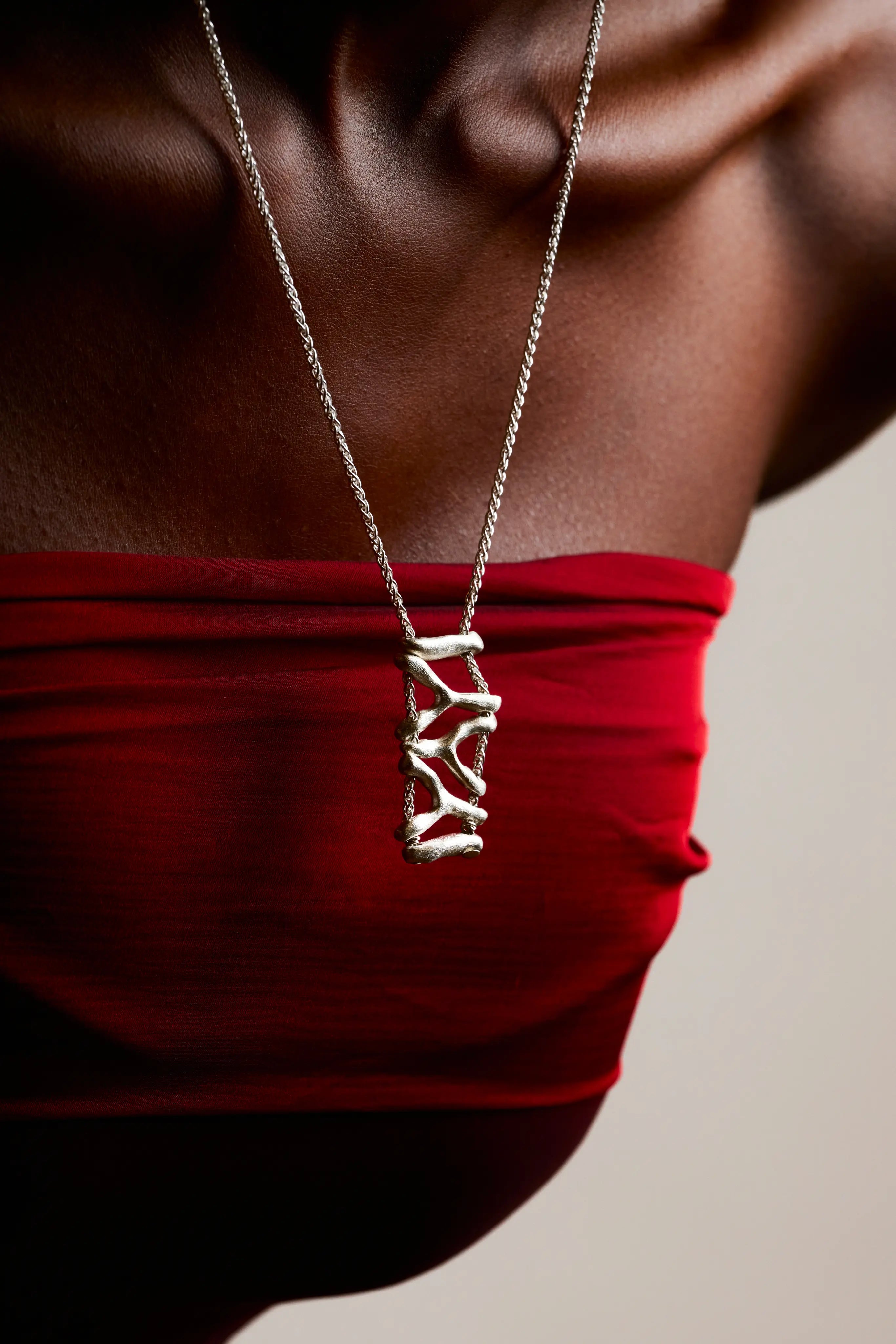 Collier Isopora Synonys en argent 925, porté sur une femme en robe rouge. Bijou fait main, collection Corail éthique.