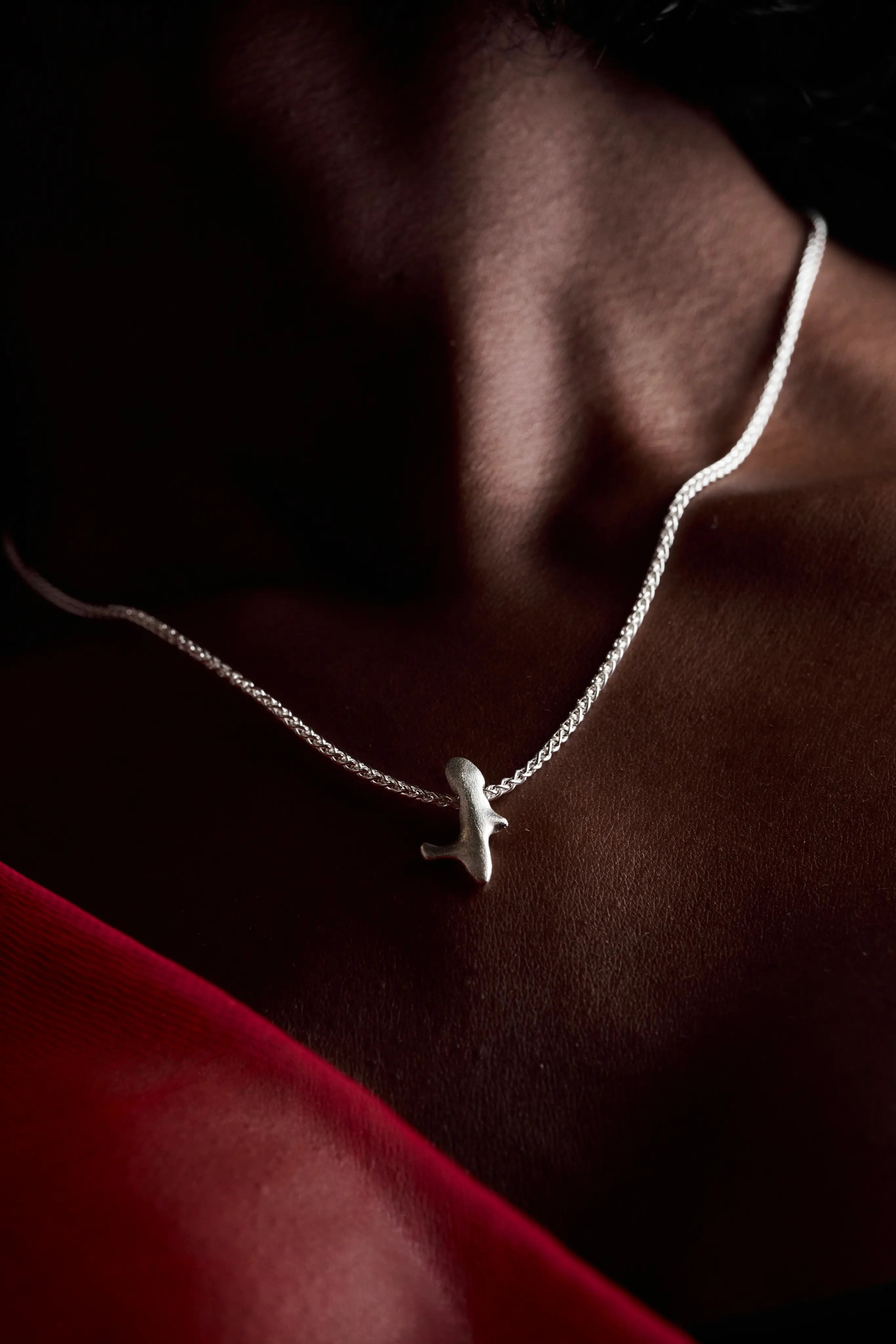 Femme portant le collier Skel en argent sur le décolleté avec un vêtement rouge.