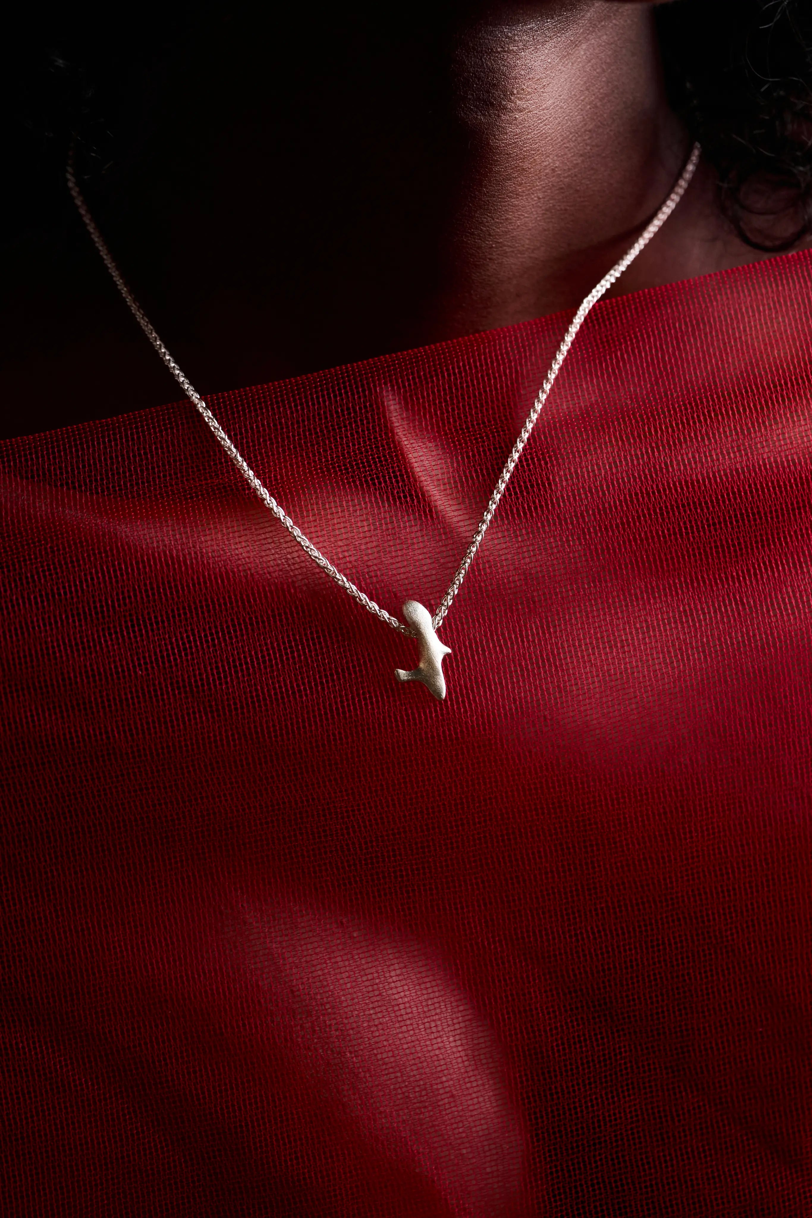 Gros plan sur le pendentif Skel porté, accentuant l'éclat de l'argent 925.