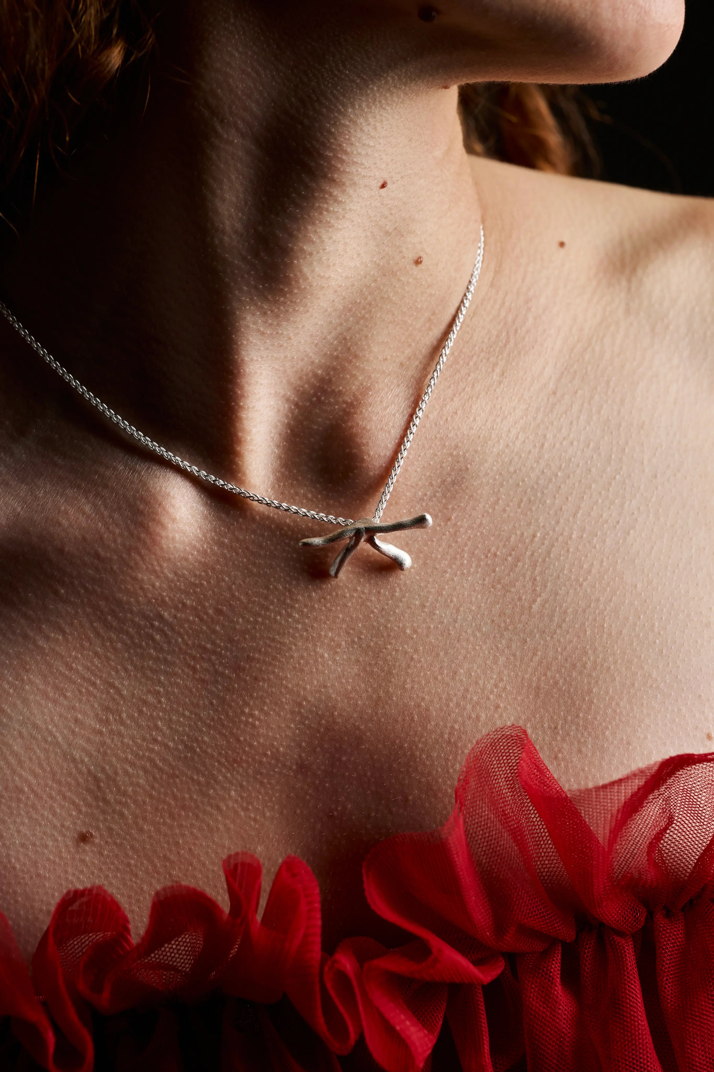 Vue du collier Stellar en argent porté sur un décolleté avec un vêtement rouge.