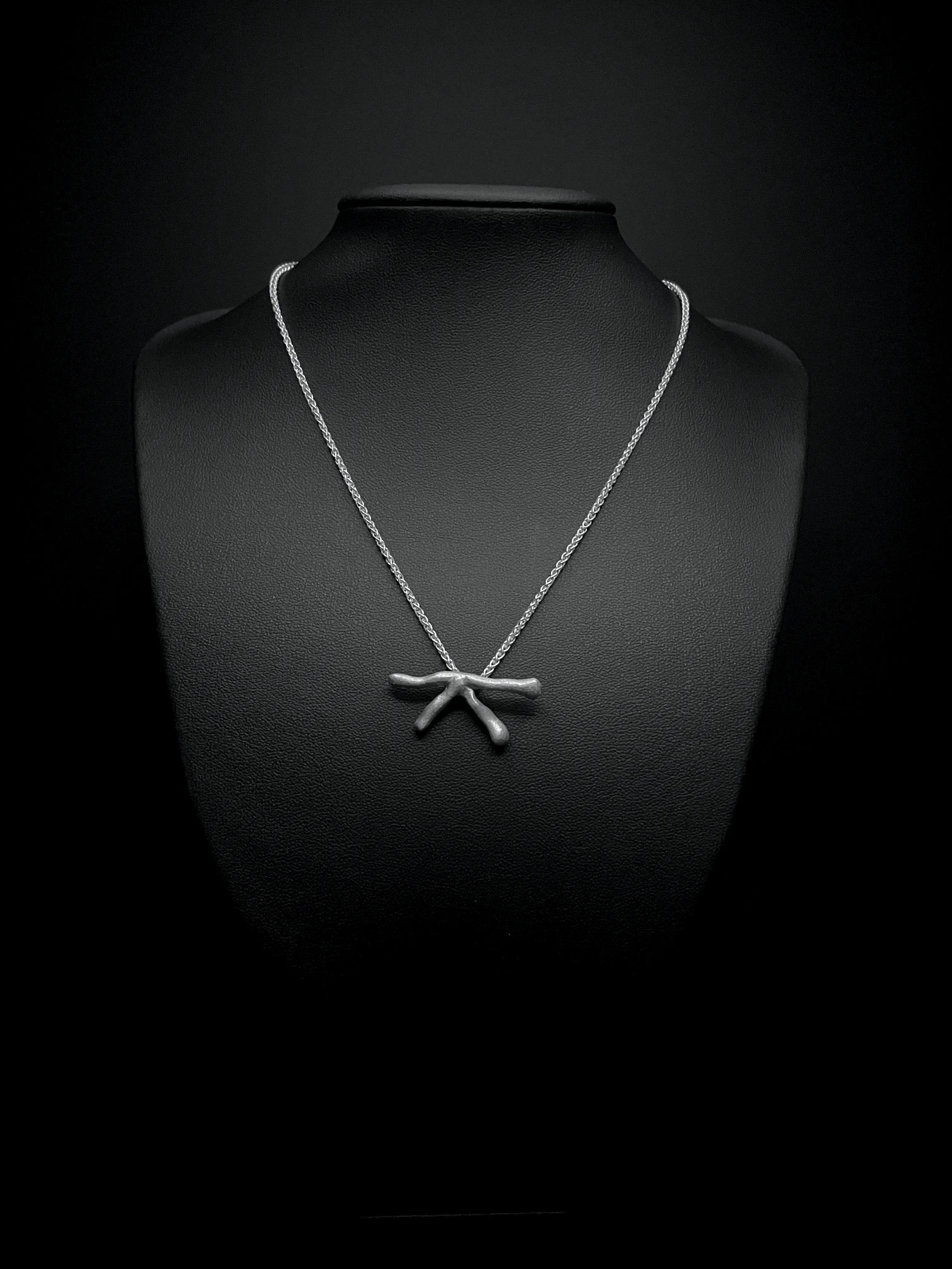 Collier Stellar en argent porté sur un buste noir, avec chaînes et pendentif visibles.